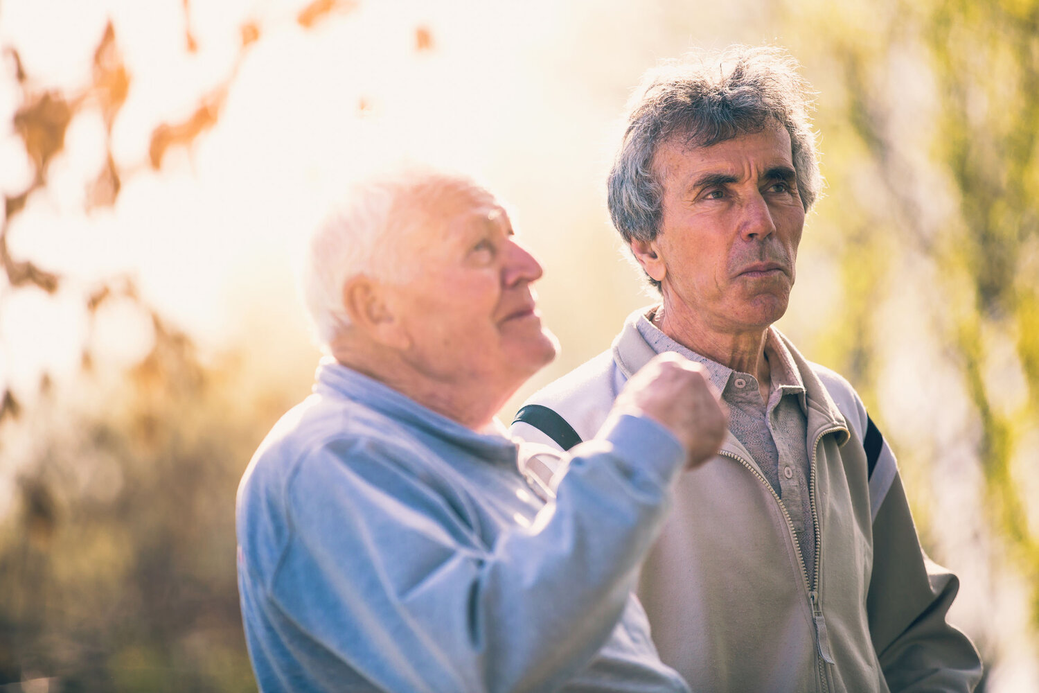 Adult son walking with his senior father in the park.